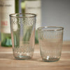 Glassware from the Colette collection features bubbles blown into the glass and vitage etching around the top and bottom rims. In this photo, there is a tall tumbler, a small tumbler.