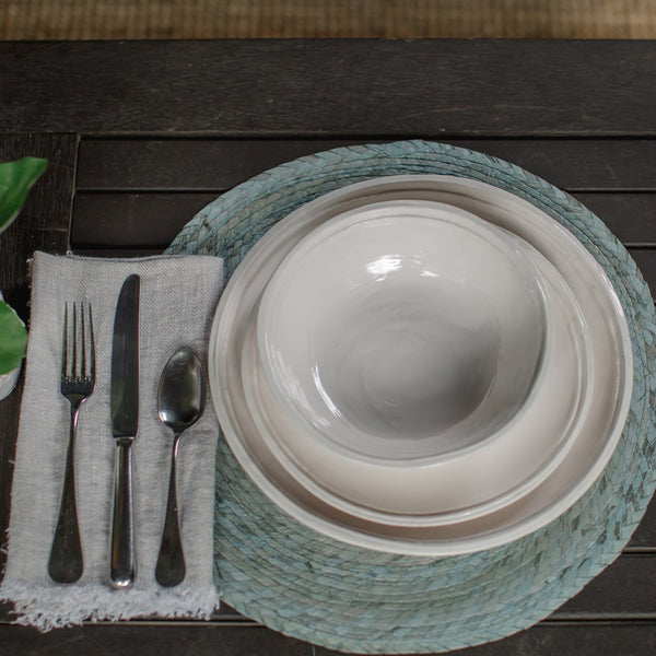 Table setting with Relish melamine Double Lined pattern. A dinner plate, salad plate and bowl on a blue placemat with napkin, fork, knife and spoon.