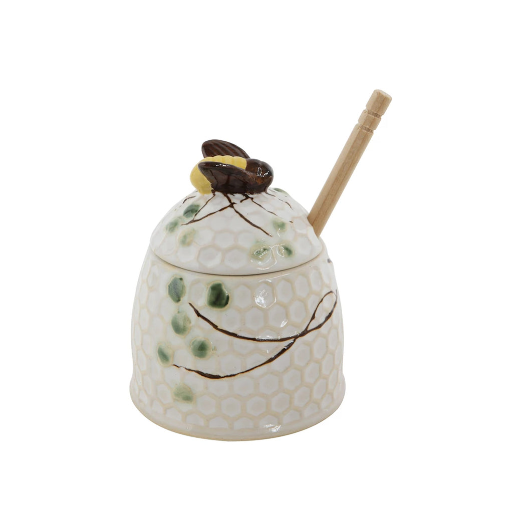 Lidded stoneware honey jar with a honeycomb texture. A hand-painted bee sits on the lid and leaves decorate the jar. Comes with a wooden honey dipper.