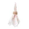 Juliska Provence woven rattan napkin ring around a white and pink napkin. This napkin ring is oval is shape with decorative rattan loops.