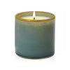 Lafco's Sea & Dune candle is housed in a hand-blown blue glass vessel with a honey-colored rim. The candle's one wick is lit.