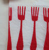 Close-up of a tea towel with a natural color ground and red forks hand stamped on the  edge.