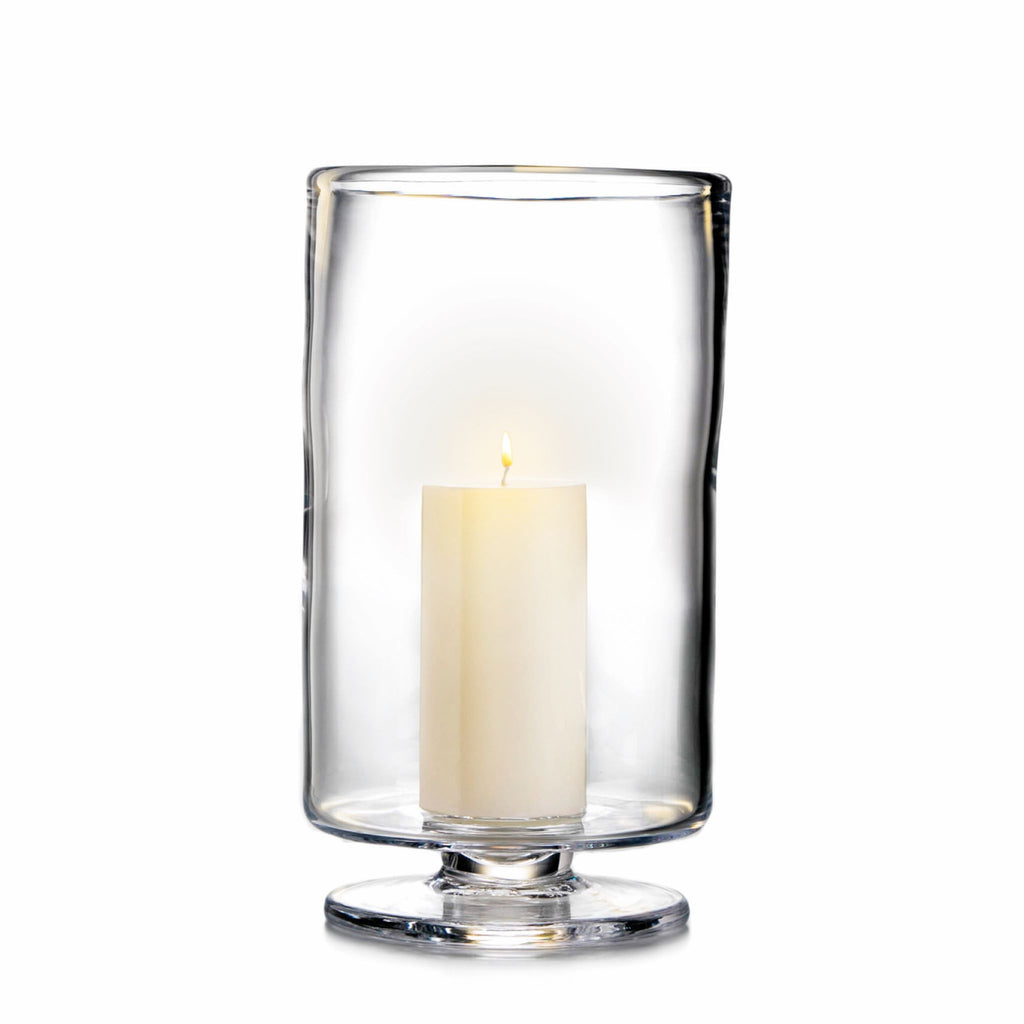 Simon Pearce Nantucket hurricane with included pillar candle placed inside. This round candleholder is handmade of clear glass, is 13 inches high and 8.25 inches wide, has a wide, raised base, and straight sides.
