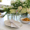 Pair of cream Relish melamine salad serving spoons atop two Relish serving trays on a table set with flowers and food.